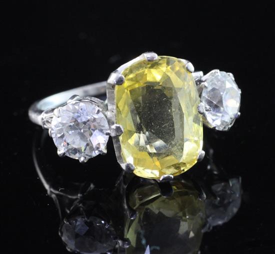 A platinum and three stone yellow sapphire and diamond ring, size O.